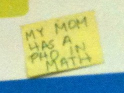 Close up of yellow sticky note that says, 'My mom has a PhD in math'
